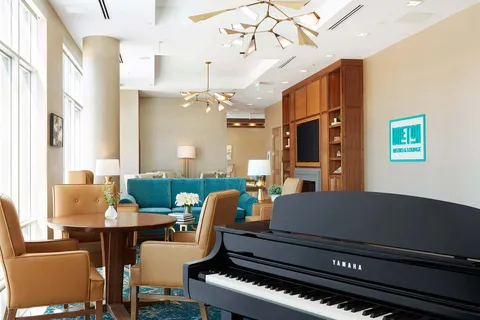 Piano beside lounge seating and tall windows