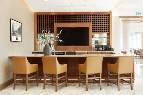 Bar counter and lounge seating beneath a wall mounted screen