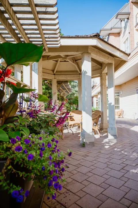 Covered garden seating area with flowers and brick paving.