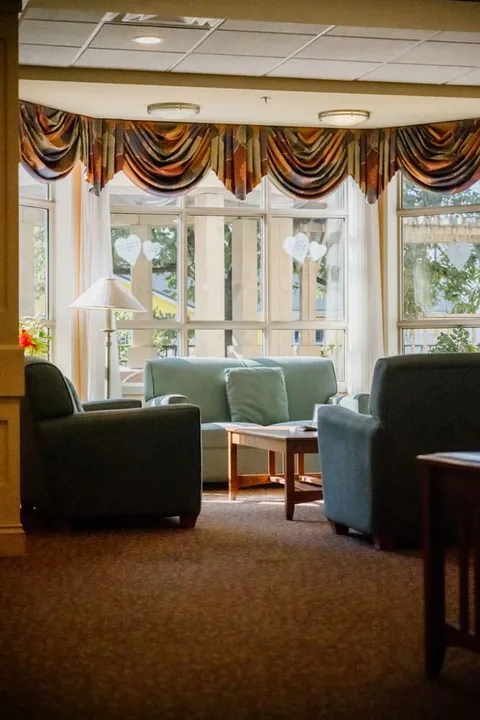 Lounge chairs and a coffee table beside large windows.