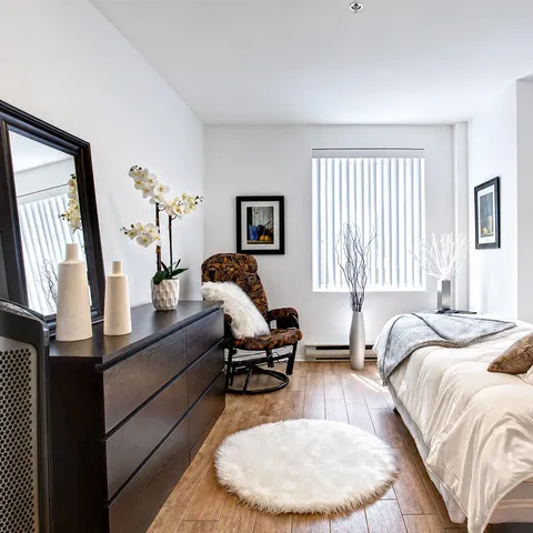 Bedroom with a bed, rocking chair, dresser, mirror and plants
