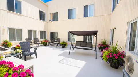 Courtyard with outdoor chairs, a covered swing and flower-filled planters