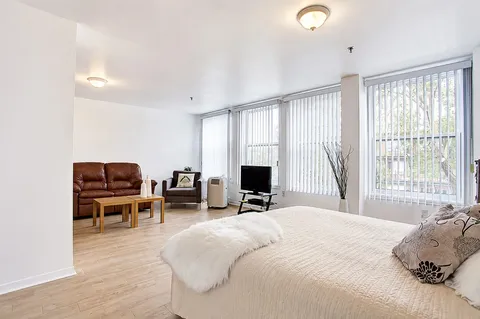 Bedroom with a bed, sofa, armchair, television and large windows