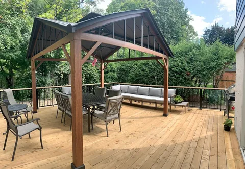 Wooden deck with covered lounge seating and outdoor table.