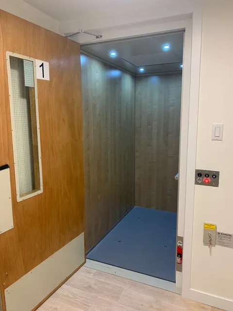Residential lift with an open door beside the hallway.