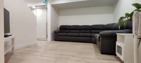 Living area with a sectional sofa, television and floorboards.