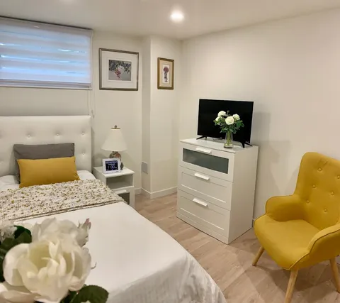 Bedroom with a single bed, yellow chair and dresser.