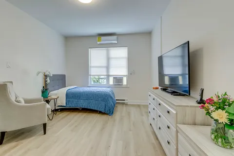 Suite with a bed, armchair, dresser, television and window.