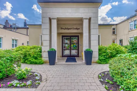 Trafalgar Lodge entrance with planters and a paved path through flower beds.