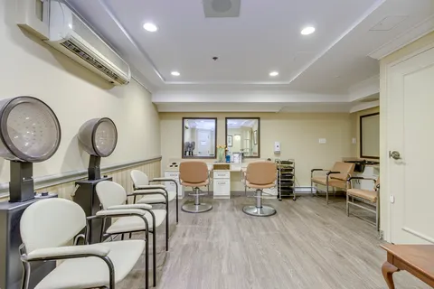 Salon with chairs, wall mirrors and hooded hair dryers.