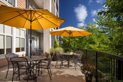 Patio with yellow umbrellas, tables and flower planters beside the residence