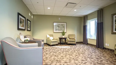 Armchairs beside framed landscape pictures and a large window