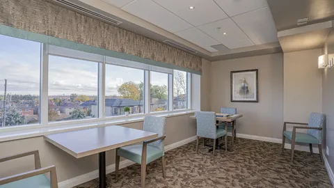 Tables and chairs beside large windows overlooking nearby buildings