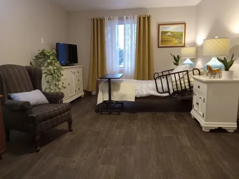Bedroom with an adjustable bed, armchair, white dressers and a television