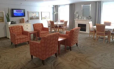 Room with orange armchairs, tables, large windows and a fireplace