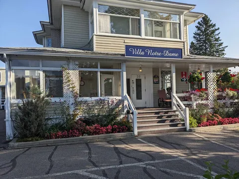 Front of the residence with an enclosed porch, entrance steps and flower beds.