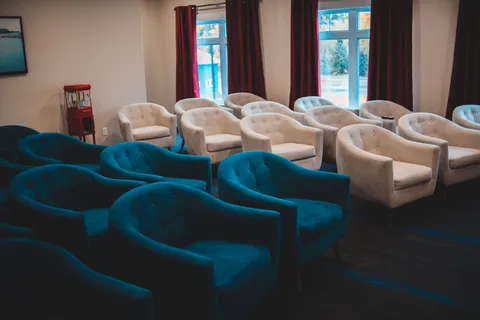 Rows of armchairs beside curtained windows.