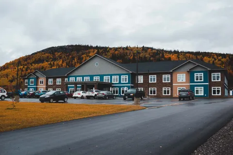 Residence frontage with parked vehicles and autumn hillside behind.