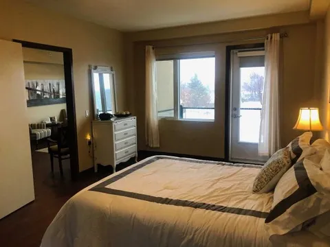 Bedroom with a bed, dresser and glass door beside a window