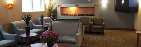 Lounge with grey armchairs, small tables and a fireplace