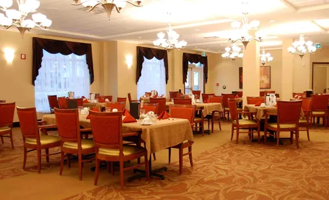 Dining room with tables, wooden chairs and large curtained windows