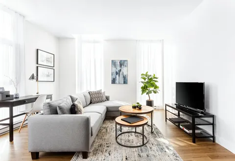 Sitting room with a grey sofa, nested coffee tables, television and large windows