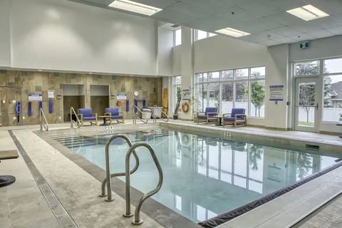 Indoor swimming pool with a lift and large windows.