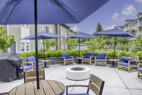 Patio with sofas, umbrellas and a circular fire table.