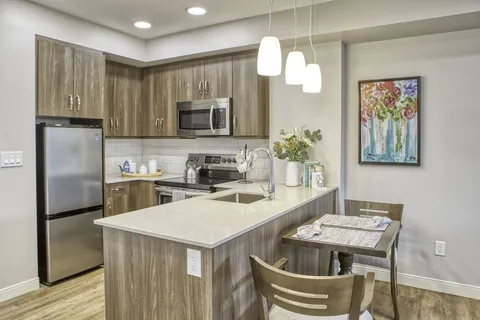 Suite kitchen with an island, appliances and pendant lights.