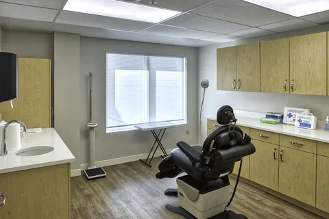 Salon with a styling chair, cabinets and window.