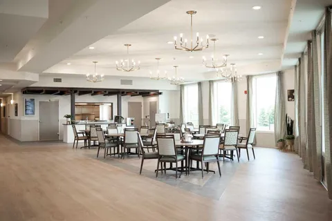Dining room with tables, chairs, chandeliers and large windows