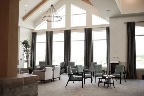 Armchairs beneath tall windows and a vaulted ceiling