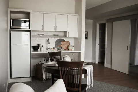 Kitchenette with white cabinets beside a round dining table