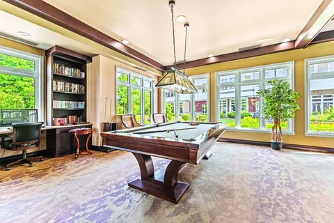 Billiards table beside bookshelves and large windows