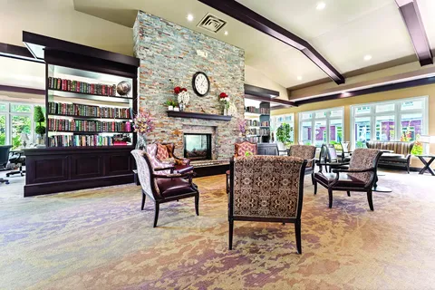 Armchairs around a stone fireplace beside bookshelves