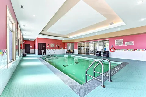 Indoor swimming pool with tiled surround and metal handrails