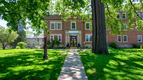 Brick residence and front walkway beneath mature trees