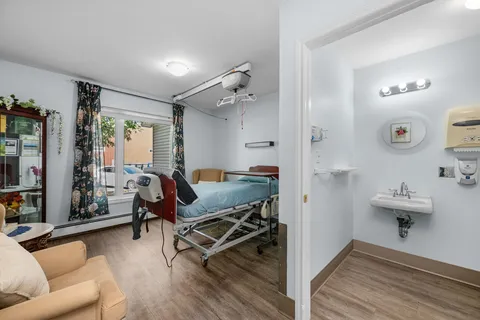 Bedroom with an adjustable bed, ceiling lift, armchairs and a sink