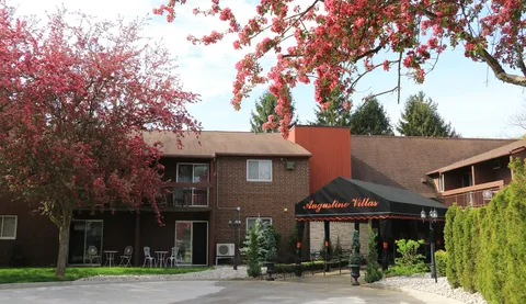Brick residence with a covered entrance, flowering trees and a driveway