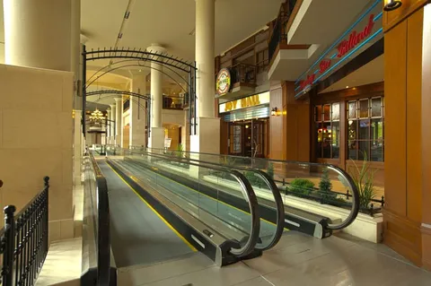 Indoor concourse with moving walkways, railings and storefronts