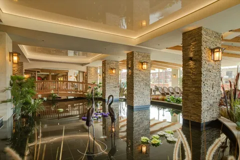 Indoor pond with a wooden footbridge, stone columns and planted borders