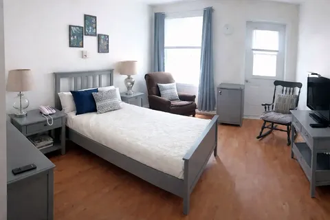 Suite with a bed, armchairs, television and window.