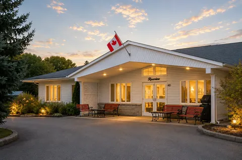 Residence entrance facade with benches, flower beds and a Canadian flag.