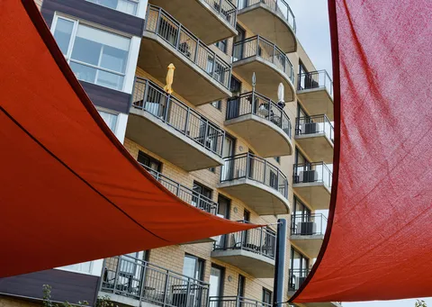 Residence balconies seen between orange fabric shade sails