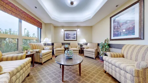 Striped armchairs and a sofa beside windows and a round table