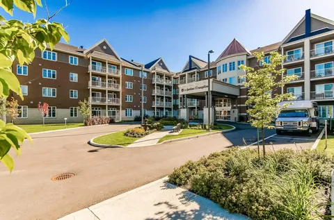 Brick residence with balconies, covered entrance, a driveway, flowerbeds and a parked minibus