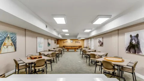 Games room with tables, chairs, board games and a pool table at the far end