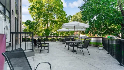 Patio with tables, chairs, white umbrellas and a black railing