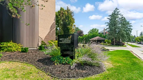 Landscaped planting bed with a residence sign beside the building and sidewalk