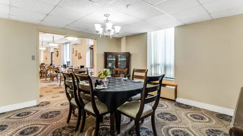 Dining room with a round set table, dark wooden chairs and a glass-fronted cabinet